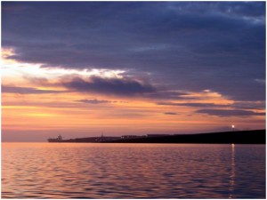 Flotta at dawn, oil refinery flare to the right and tanker to the left.
